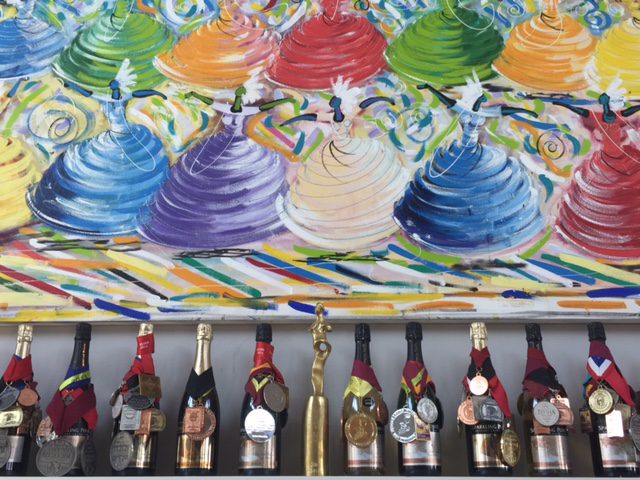 A painting of colorful cakes and wine bottles.